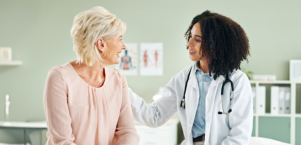 A doctor listens to a happy patient in the exam room.