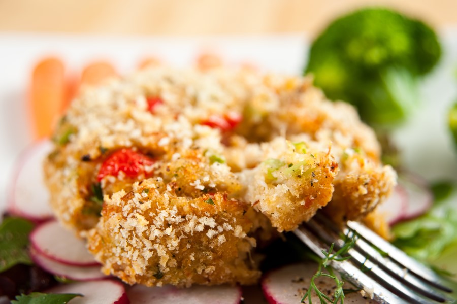 crab cakes with red peppers on a bed of lettuce and radishes for garnish