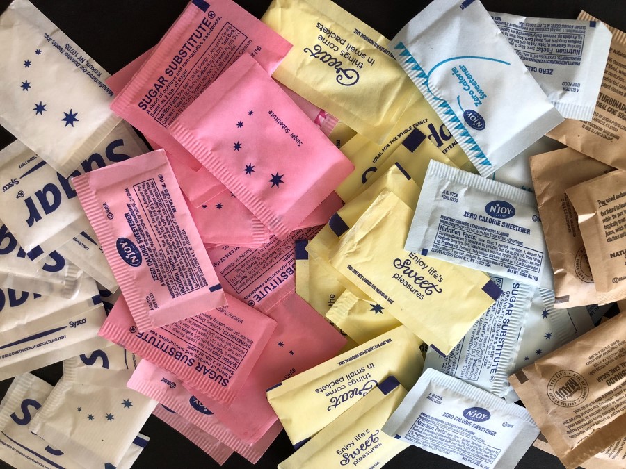 several different colorful sweetener packets on a table
