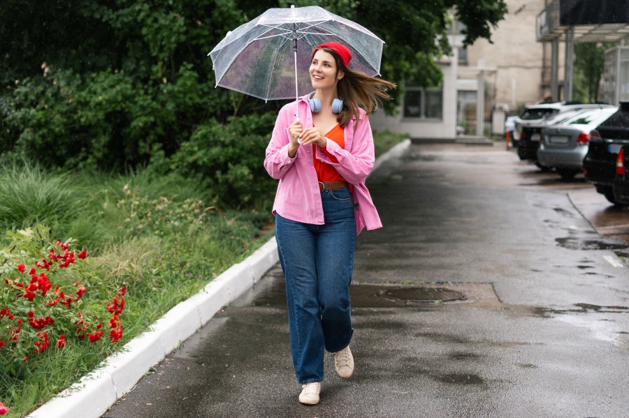 smiling woman walking near a garden with umbrella
