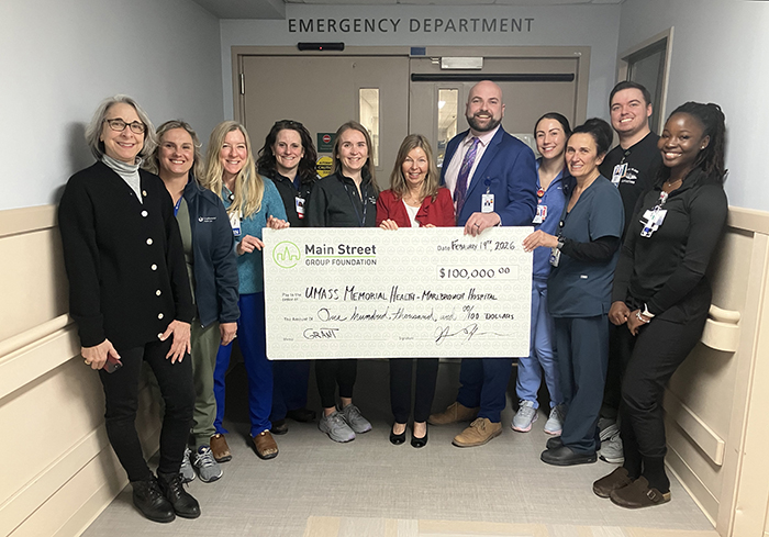 A group of caregivers hold up a large-sized check for $100,000.00