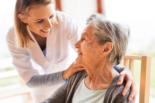A caregiver visits an elderly patient at home