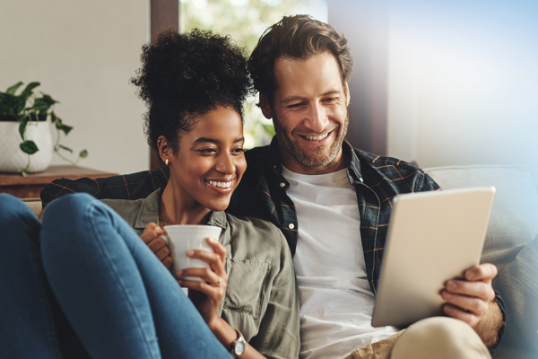 A couple relaxes together and watches a shared tablet screen