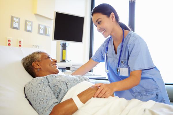 A nurse checks on her patient who is lying in bed.