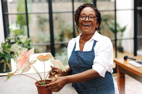 A smiling senior woman cares for her plants