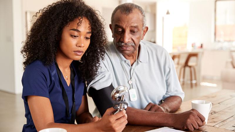 Doctor takes patient's blood pressure in patient's home.