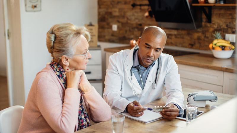 Doctor discusses treatment with patient in her home.