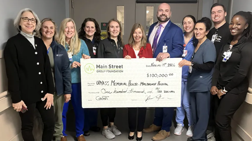 A group of caregivers at the Marlborough Campus hold up a large-size check.