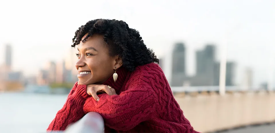 happy woman looking at a river with a city skyline in the background