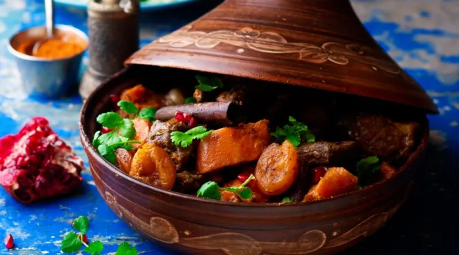 lamb butternut squash and apricots in a tagine on a blue tablecloth