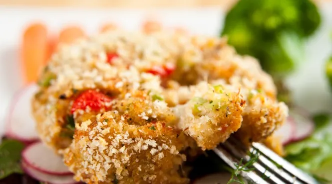crab cakes with red peppers on a bed of lettuce and radishes for garnish