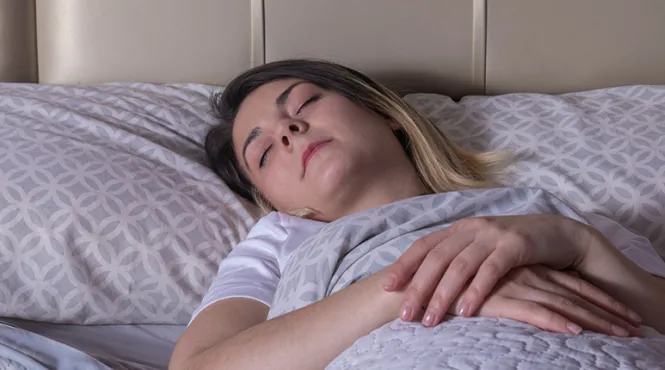 A woman sleeps on her back with help from mindfulness.