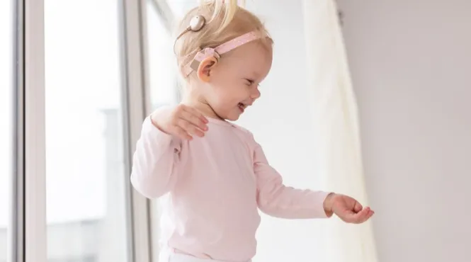 Toddler girl with cochlear implant smiling as she is discovering the world around her