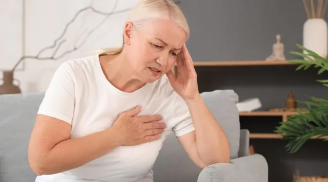 woman on couch holding sore arm caused by lymphedema after cancer.