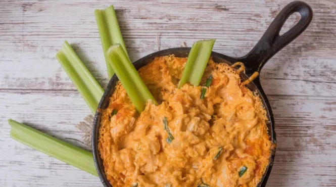 Skinny buffalo chicken dip in a skillet served with celery