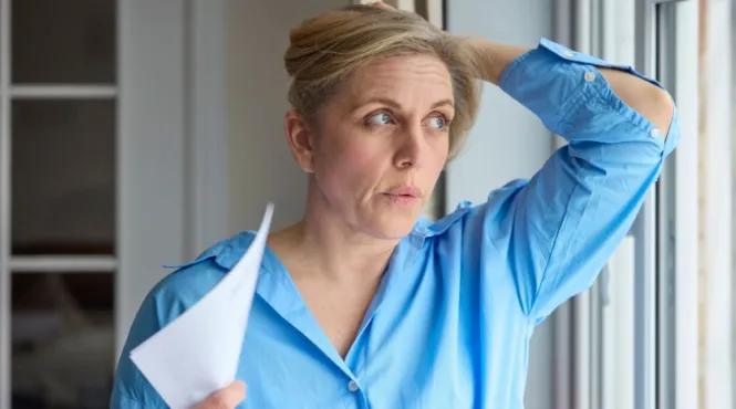 A woman having a hot flash fanning herself trying to manage menopause symptoms