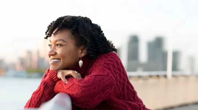 happy woman looking at a river with a city skyline in the background
