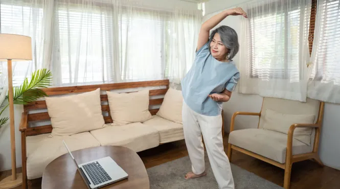 woman stretching with laptop doing at home virtual cardiac rehab