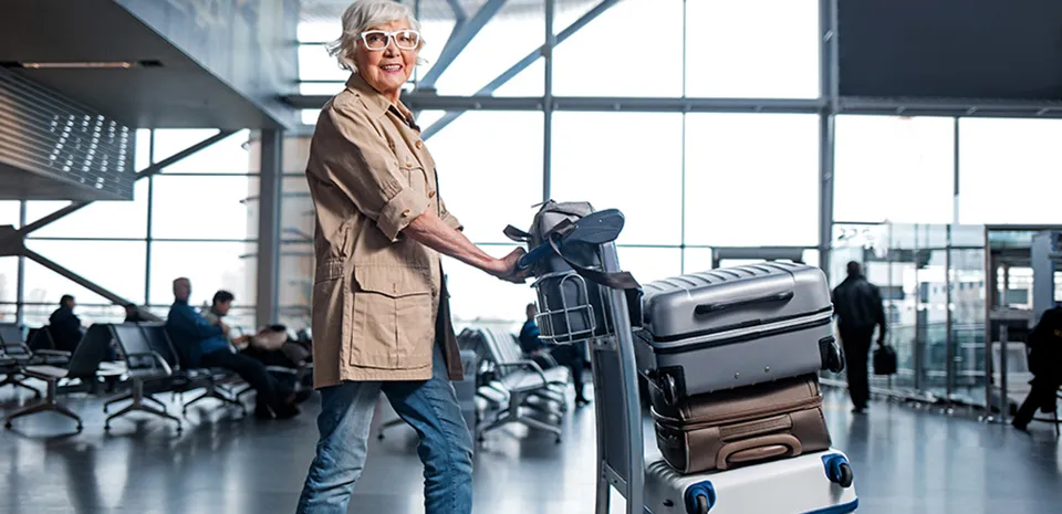A woman pushes a cart with her luggage through an airport.