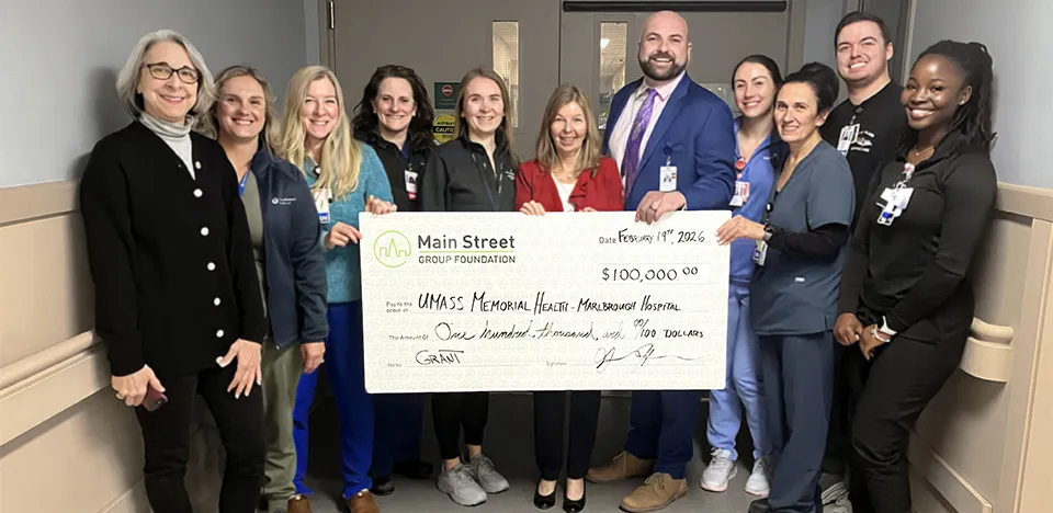 A group of caregivers at the Marlborough Campus hold up a large-size check.