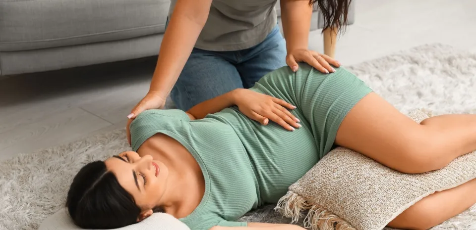Doula relieving pregnancy stress by giving a massage to a woman 