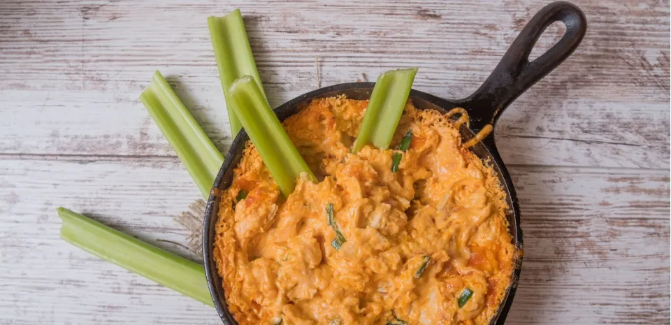 Skinny buffalo chicken dip in a skillet served with celery
