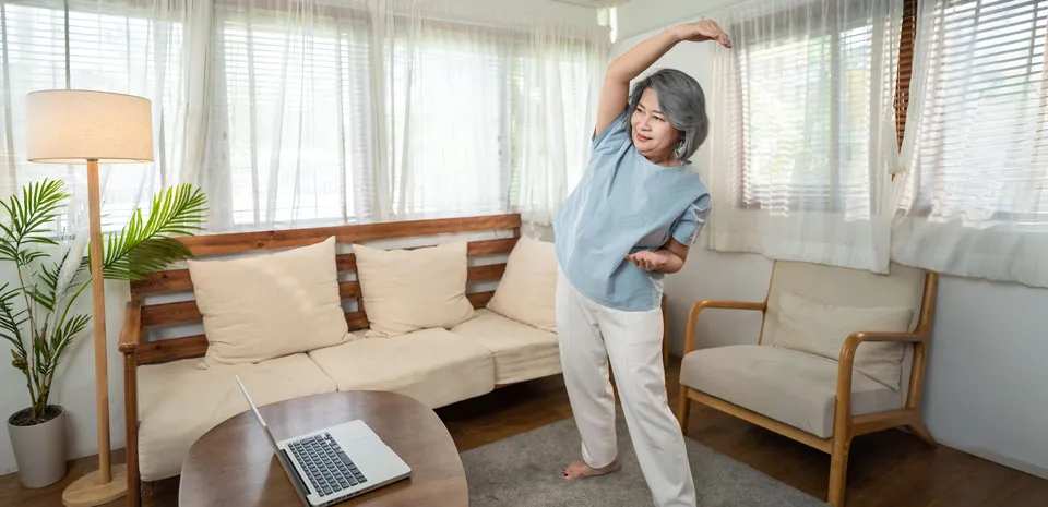 woman stretching with laptop doing at home virtual cardiac rehab