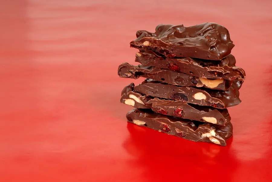 A stack of chocolate cherry bark is on a red table.