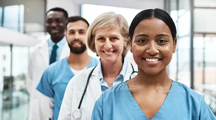 Diverse group of four medical professionals in scrubs lines up diagonally