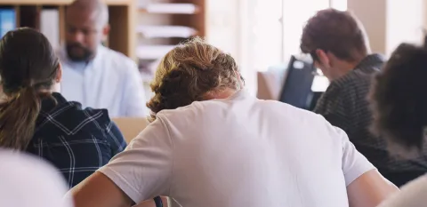 A view of students and teacher in a high school classroom, taken from the back corner.