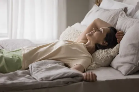 a woman lying comfortably in bed performing a body scan for mindfulness