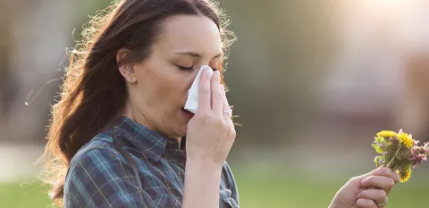 girl blowing nose and sneezing from pollen