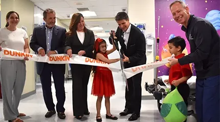 A recent patient helps to cut the ribbon at the Children's Medical Center outer space-themed surgery wing.