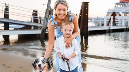 Kara Lionetta, cancer survivor who spoke at the Strut for a Cause event, poses along the shore with one of her chilren and the family dog.
