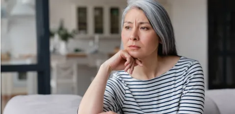 A sad woman staring on a couch needing to improve her mental health
