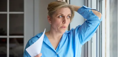 A woman having a hot flash fanning herself trying to manage menopause symptoms