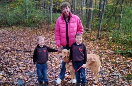 Female patient Jawan Betts stops to pose while on a walk in the woods with her two young grandsons and the family's golden retriever.