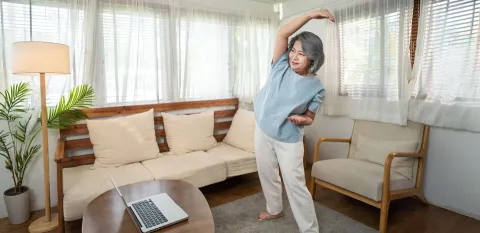 woman stretching with laptop doing at home virtual cardiac rehab