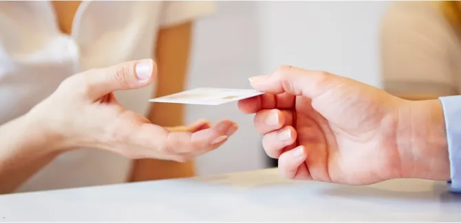 A hand on the left receives a card from a hand on the right.