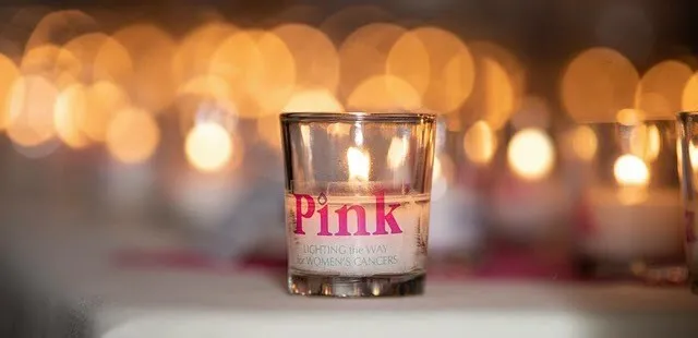 A candle with the word 'Pink' is sitting on a table.