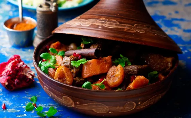 lamb and butternut squash and apricots in a tagine on a blue tablecloth