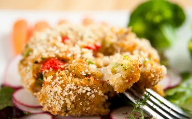 crab cakes with red peppers on a bed of lettuce and radishes for garnish