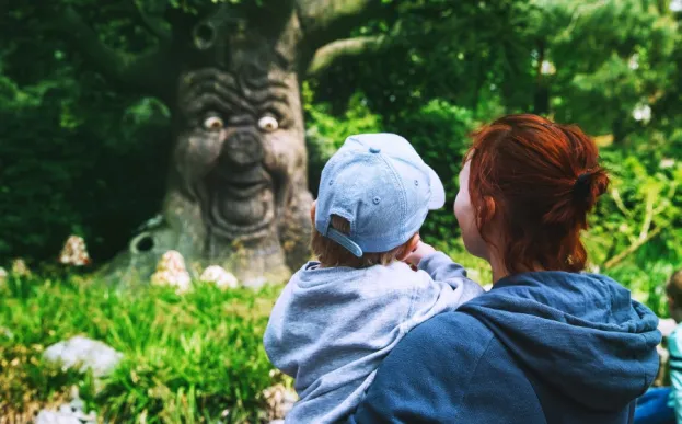 mom holding toddler near tree with a funny face sharing childhood myths