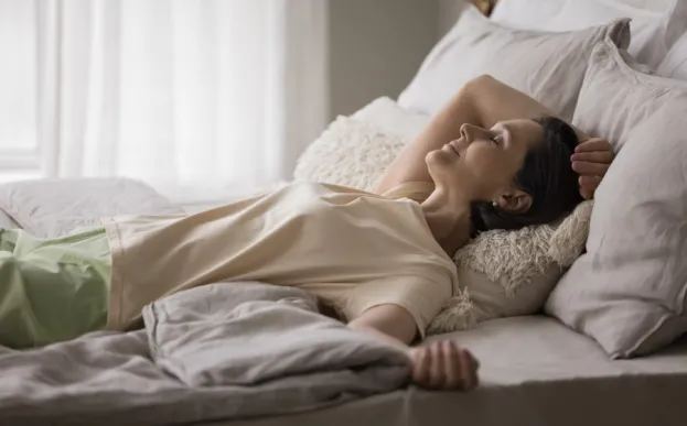 a woman lying comfortably in bed performing a body scan for mindfulness