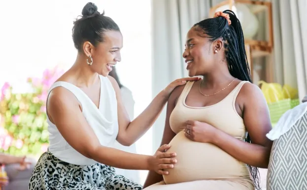 Doula with hand on smiling pregnant woman's tummy