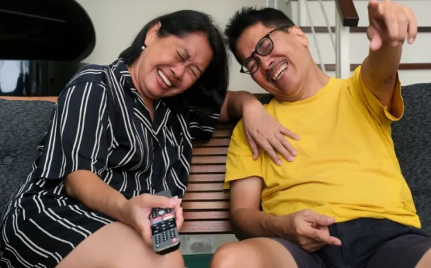 older couple watching TV and laughing which benefits heart health