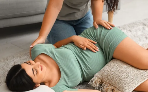 Doula relieving pregnancy stress by giving a massage to a woman 