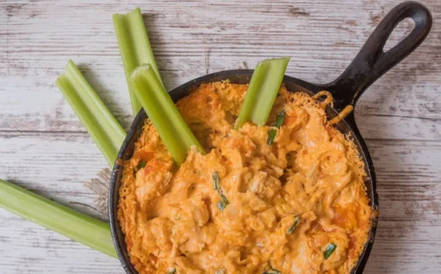 Skinny buffalo chicken dip in a skillet served with celery