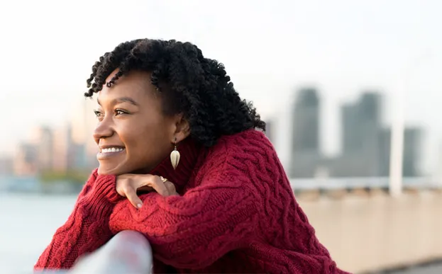 happy woman looking at a river with a city skyline in the background