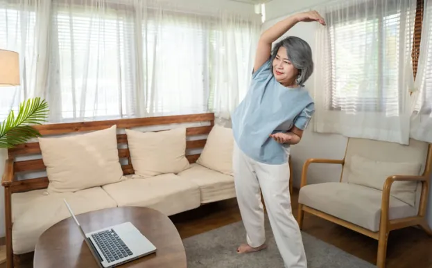 woman stretching with laptop doing at home virtual cardiac rehab
